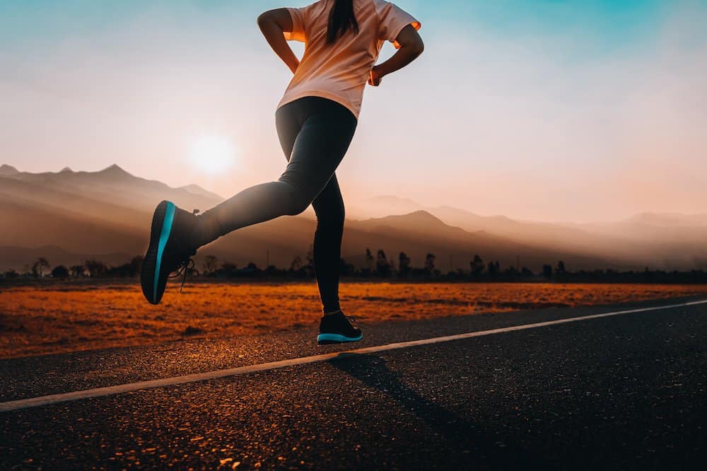 woman running on pavement during sunrise