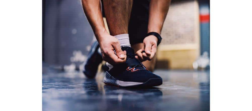 Close up of a male's hands tying shoelace in a gym. Sportsman preparing for a training